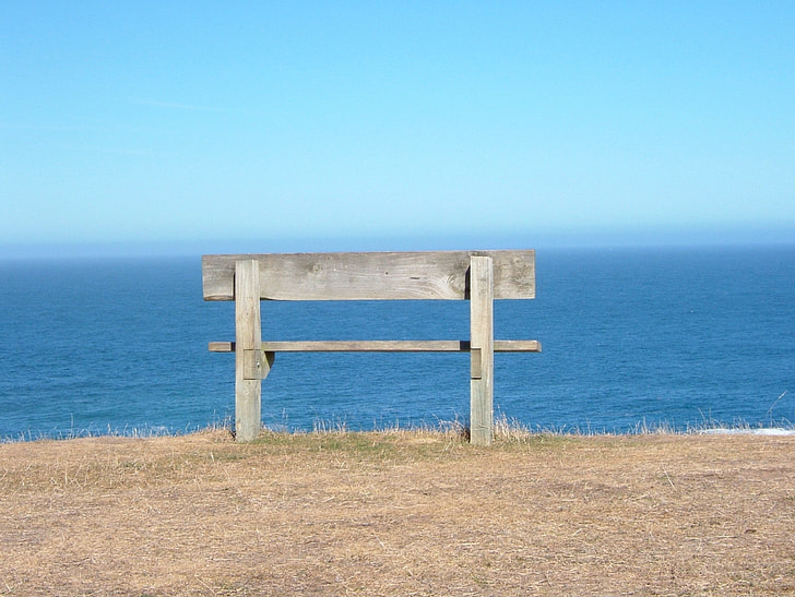 gray wooden bench near body of water