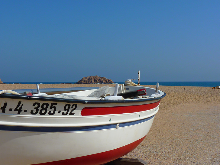white, red, and blue boat at seashore during daytime