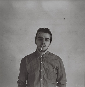 grayscale image of man with cigarette on his mouth
