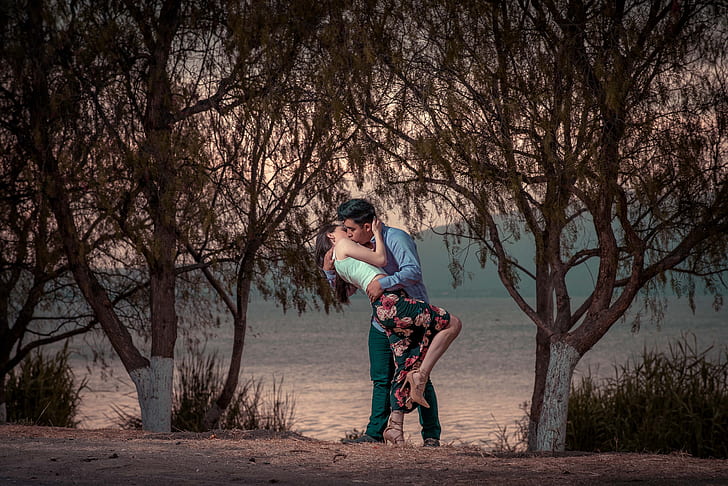couple kissing near trees during daytime