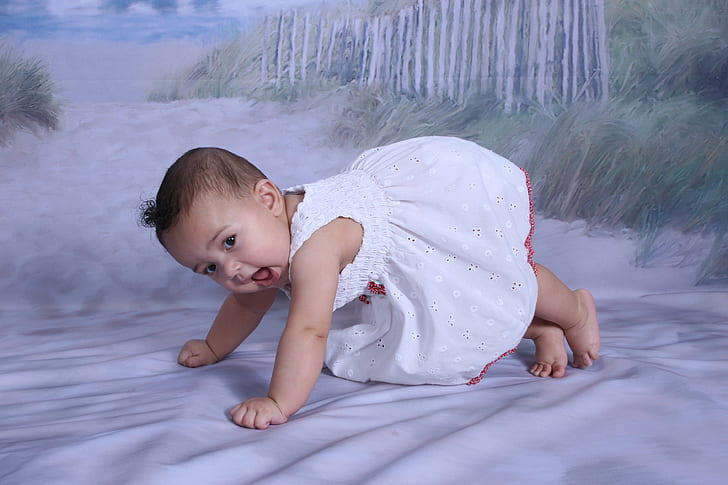 baby's wearing white floral dress planking on floor