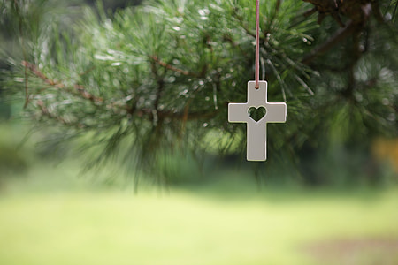 white cross pendant hanging on Christmas tree