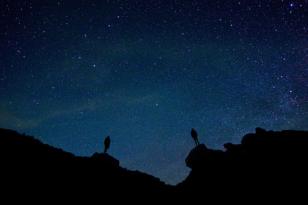 silhouette of two people with starry sky background