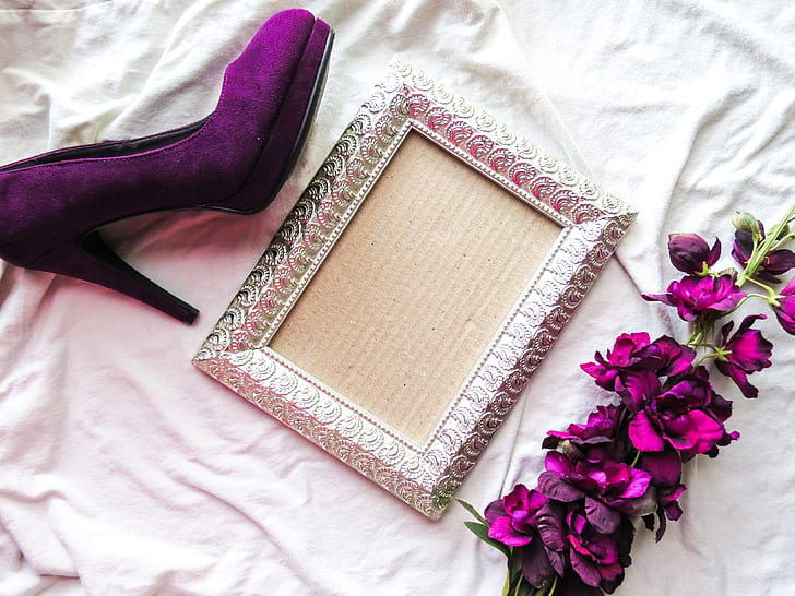 gray photo frame between purple petaled flowers and purple suede platform sandal