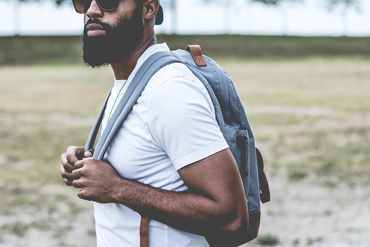 man wearing white crew-neck t-shirt and gray backpack