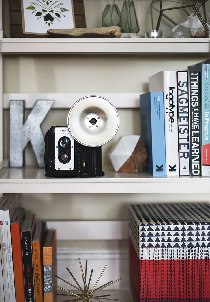 black and white instant camera on white wooden shelf