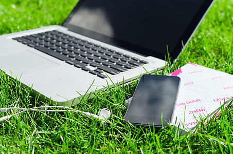MacBook Pro beside iPhone on grass