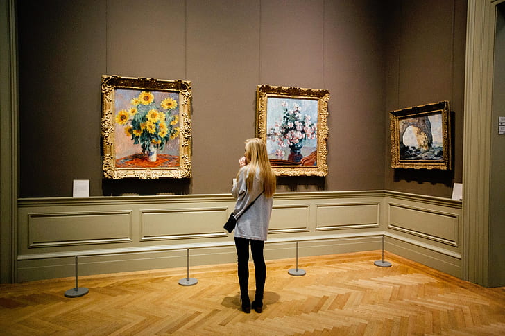 woman standing in front of three paintings
