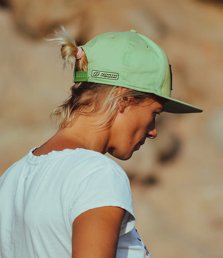 woman wearing green snap-back cap and teal cap-sleeved shirt