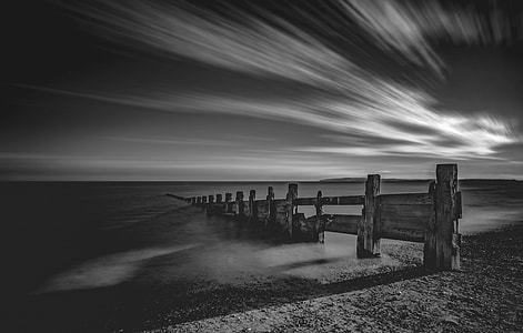 grayscale photography of brown wooden dock under clouds