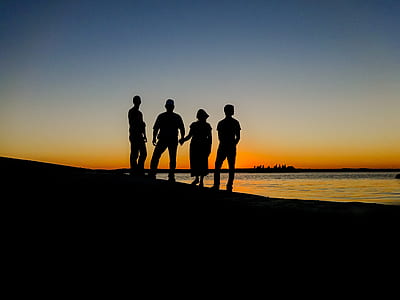 silhouette of four people standing during golden hour