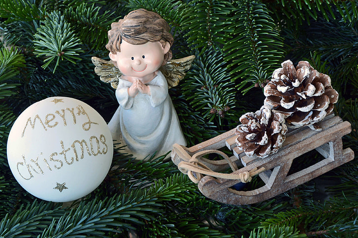 white Merry Christmas bauble beside angel figurine and brown sled