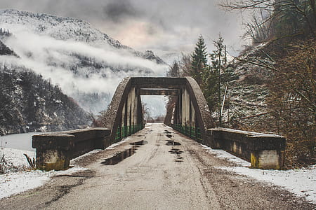 gray concrete bridge near snow covered mountain