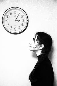 woman standing looking at wall clock