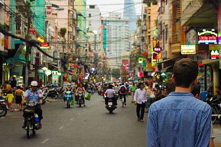 man wearing blue long-sleeved shirt walking on street during daytime