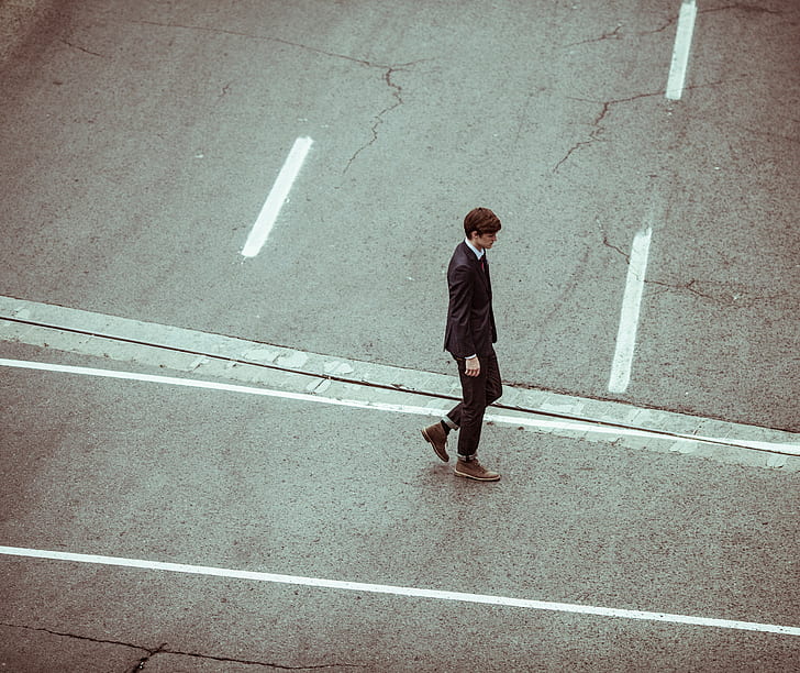 man wearing brown boots walking on road