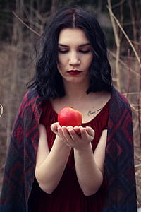 woman in red top holding apple during daytime