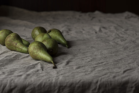 seven green oval fruits on grey textile
