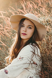 woman wearing white floral long-sleeved shirt with brown hat during daytime photo