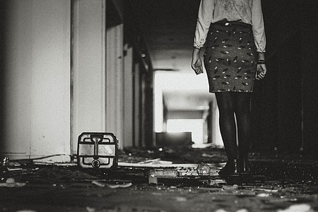 grayscale of woman standing inside building in hallway