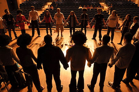 people holding hands forming circle on stage