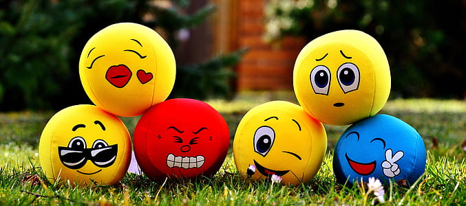 tilt-shift lens photography of six emoji balls on grass