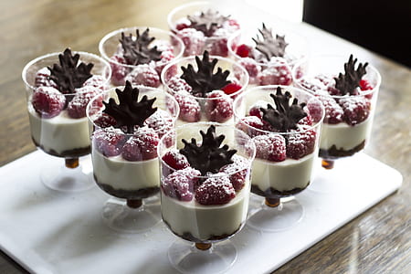 nine clear footed glasses on top of white tray filled with creams and strawberries