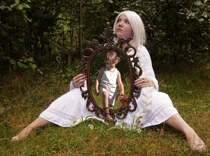 woman in white dress sitting on grass holding mirror