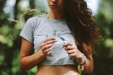 Woman in a grey crop top shirt holding wheat