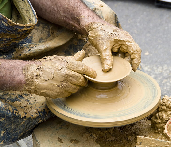 person shaping brown clay