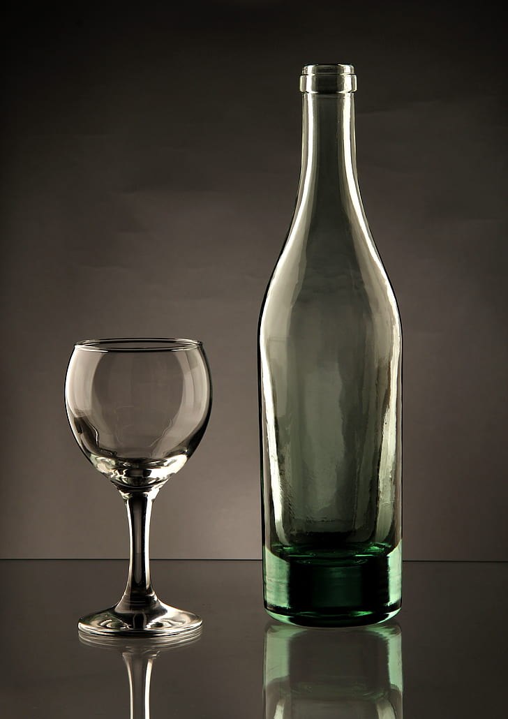 clear wine glass and teal glass bottle