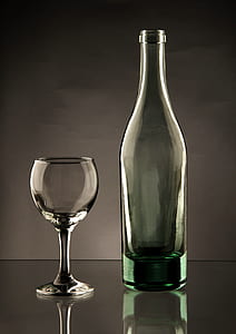 clear wine glass and teal glass bottle