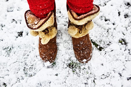 person wearing brown suede mid-calf mukluk boots at snow