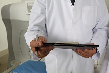 man wearing white coat holding black clipboard and pen
