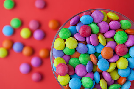 Close-up shot of a glass bowl of coloured sweets shot on a red background. Image captured with a Canon 5D DSLR