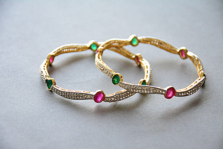 pair of gold-colored and gemstones studded bracelets