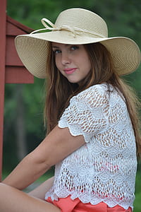 woman wearing beige sun hat and white knit top