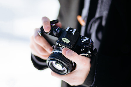 A photographer man holding a black retro camera