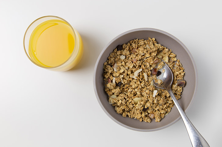 Overhead shot of a bowl of granola and a glass of fresh orange juice