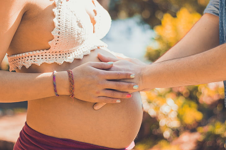 man holding womb of a pregnat woman during daytime