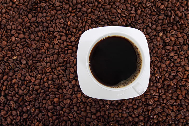 cup of coffee with saucer on coffee beans wallpaper