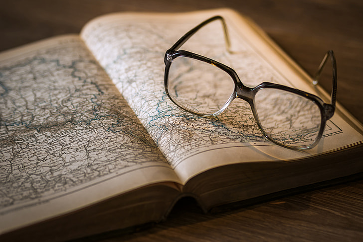 Map in open book and reading glasses