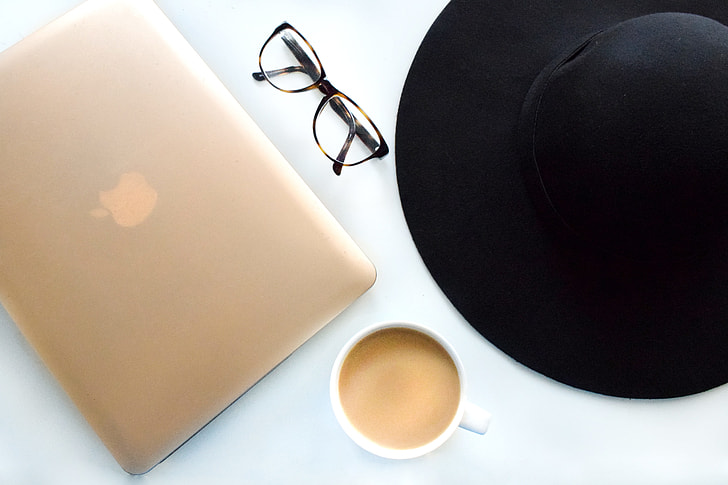 macbook beside eyeglass and mug
