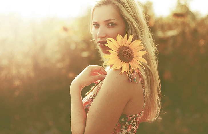 woman holding sunflower during sunset