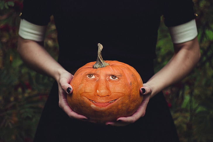 woman holds pumpkin with face