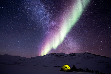 tents on snow covered terrain with purple aurora