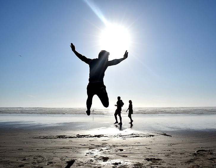 silhouette photography of person jumping against sun in seashore