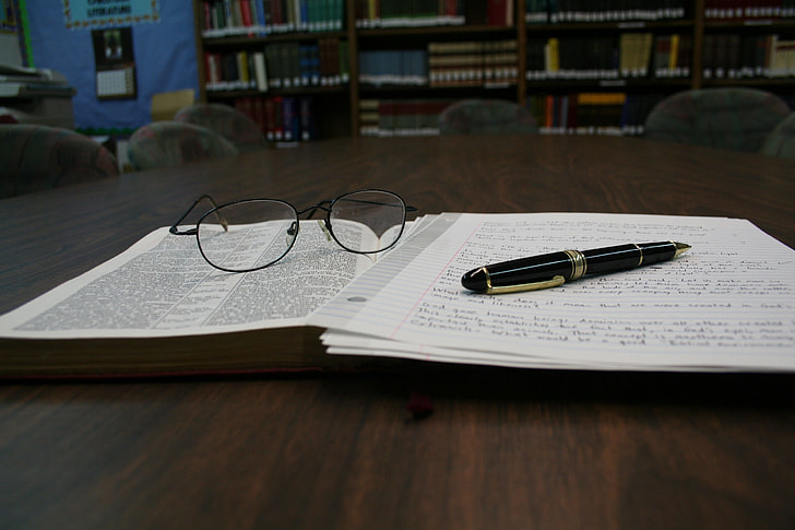 black pen beside eyeglasses on top of book