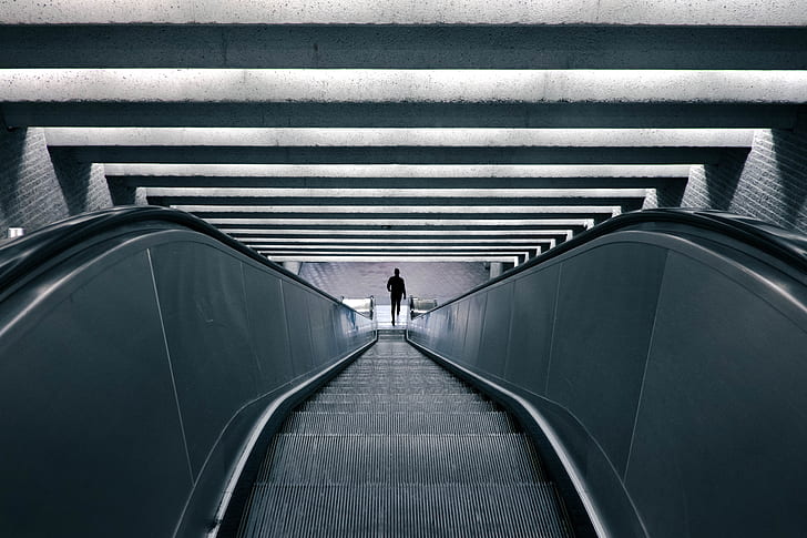photo of person standing on escalator