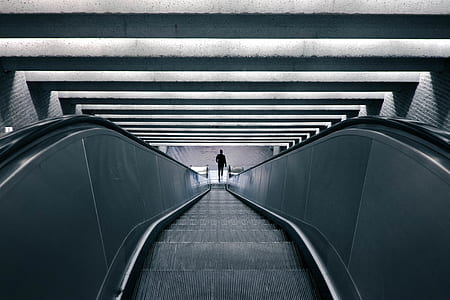 photo of person standing on escalator